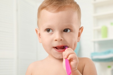 Photo of Cute little boy with toothbrush on blurred background