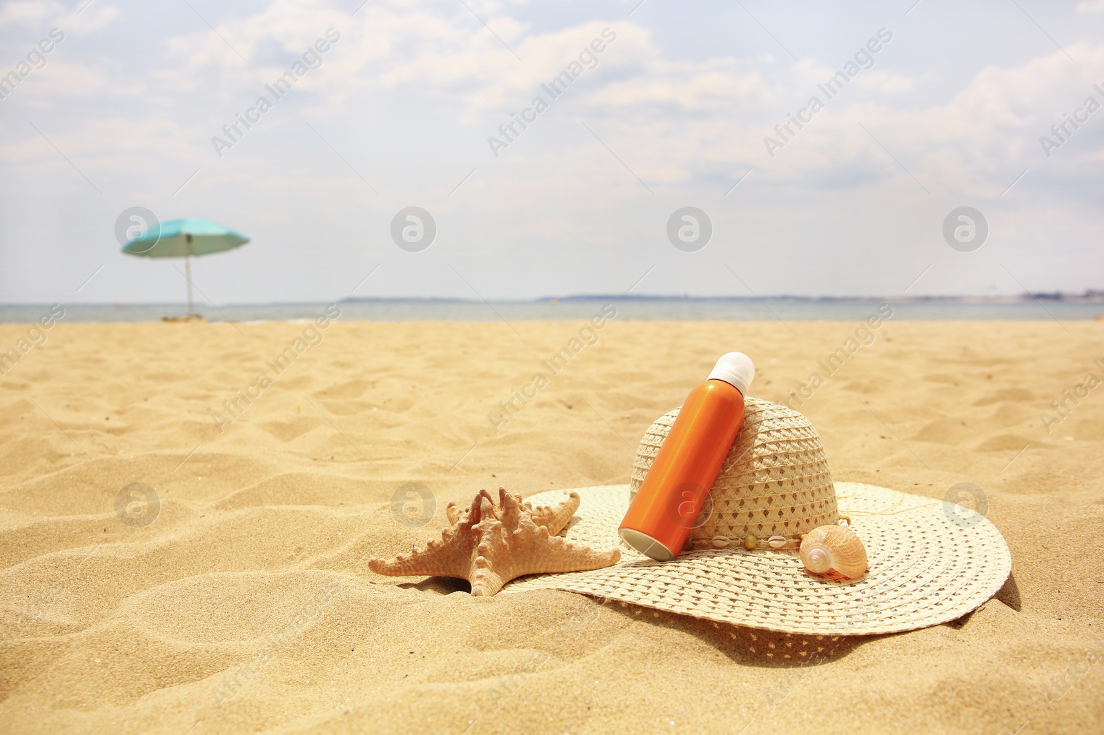 Photo of Sunscreen, hat and starfish on sand, space for text. Sun protection care