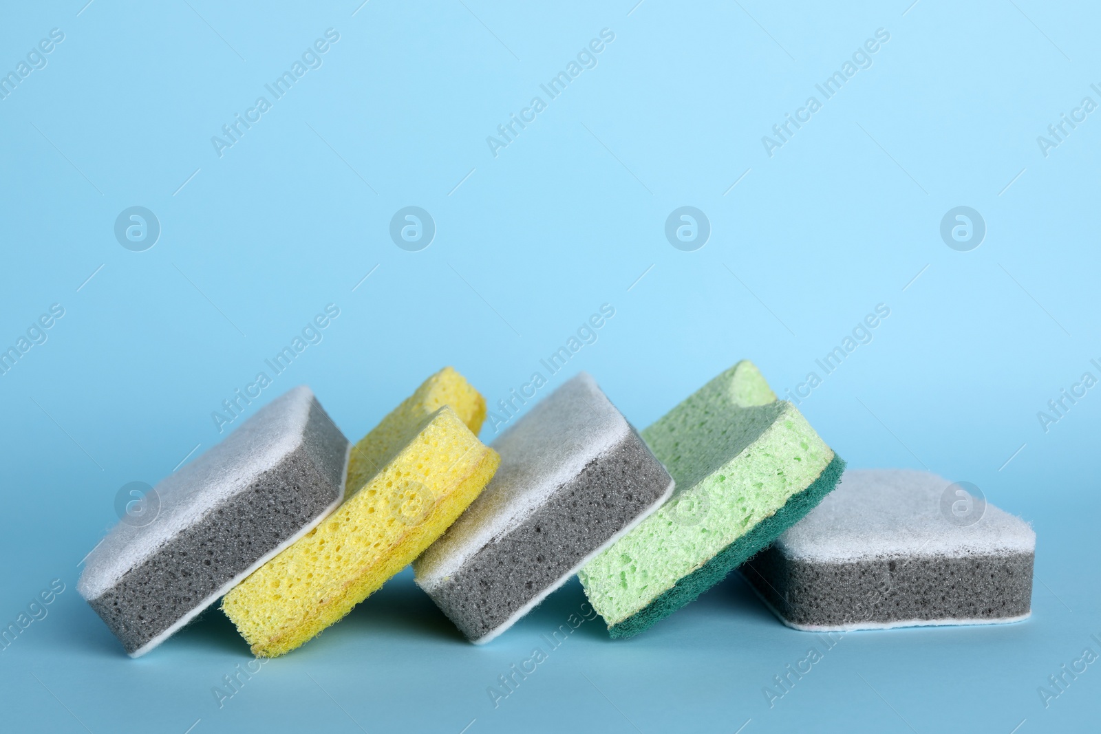 Photo of Many sponges on light blue background. Space for text