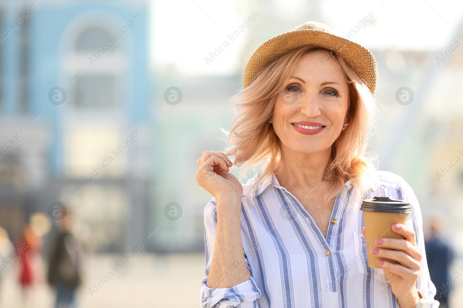 Photo of Beautiful mature woman with cup of coffee outdoors