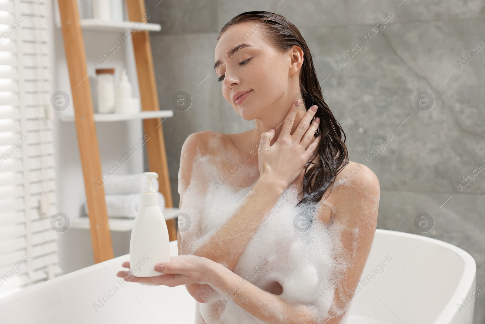 Photo of Woman taking bath with shower gel in bathroom