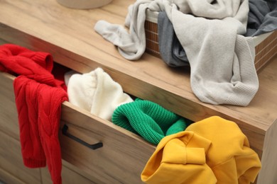 Cluttered chest of drawers indoors, closeup. Clothes in mess