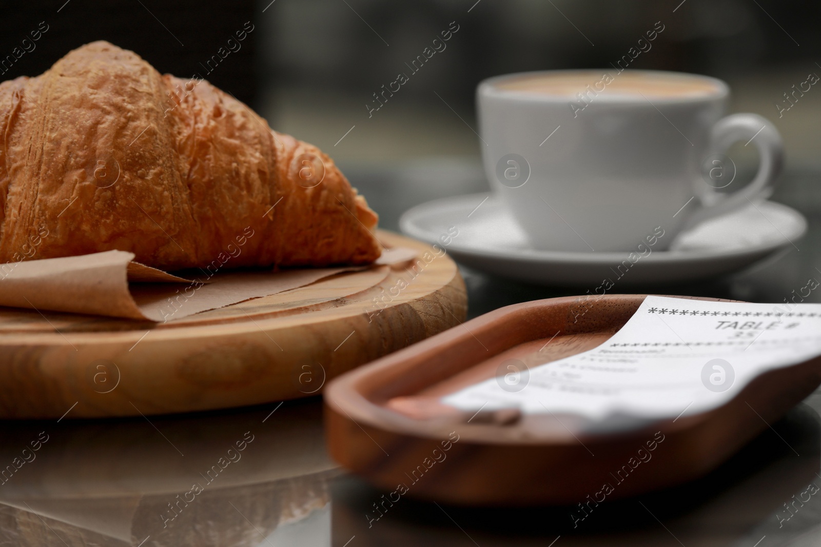 Photo of Tips and receipt near croissant on table, closeup