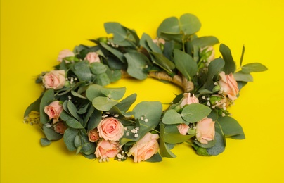 Photo of Wreath made of beautiful flowers on yellow background