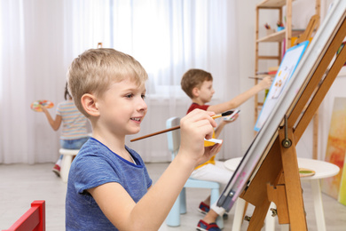 Photo of Cute little child painting during lesson in room