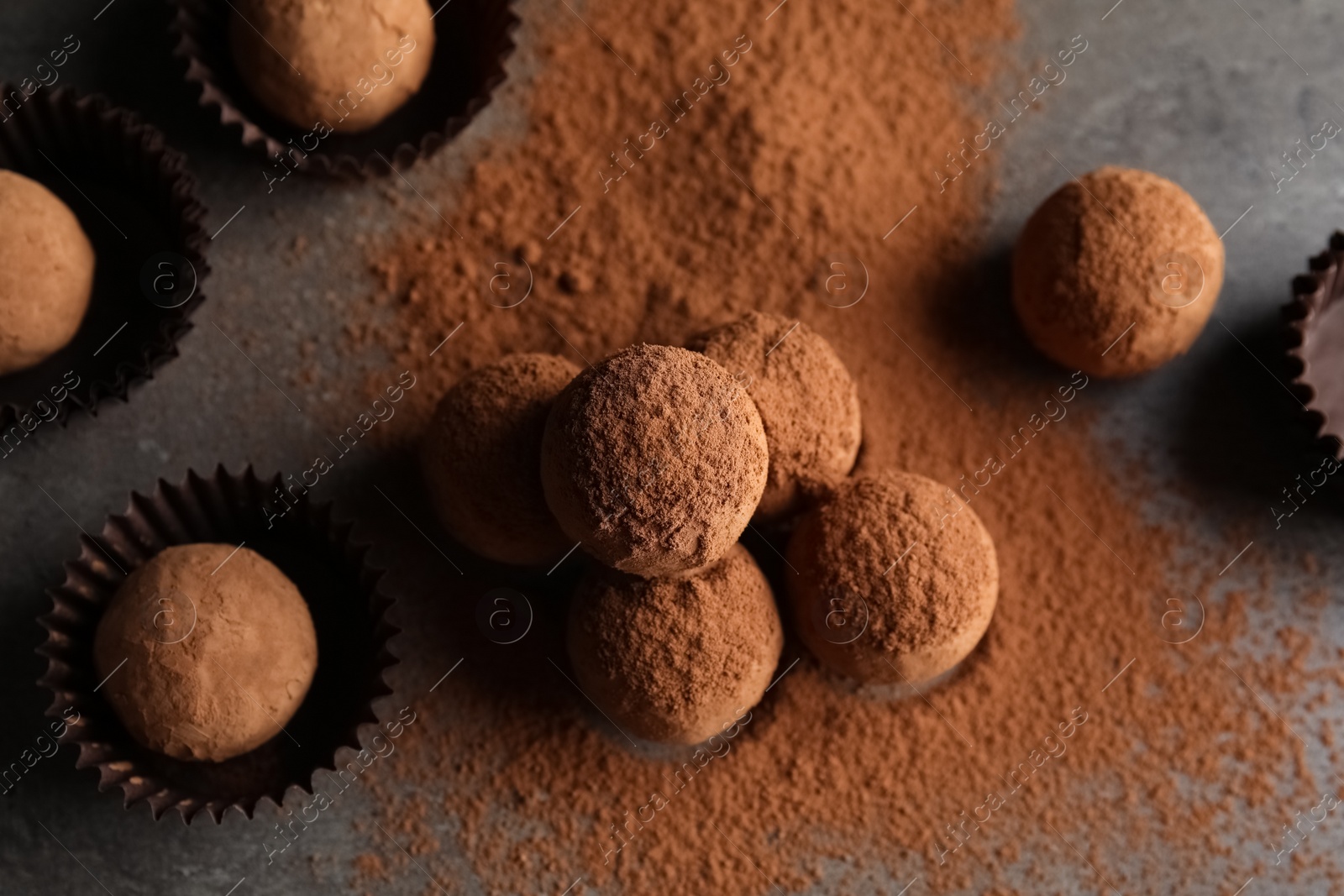 Photo of Tasty chocolate truffles powdered with cocoa on grey background, top view