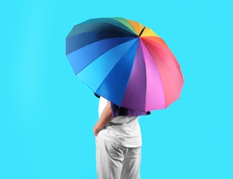 Man with rainbow umbrella on color background