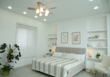 Photo of Comfortable furniture, ceiling fan, houseplants and accessories in stylish bedroom