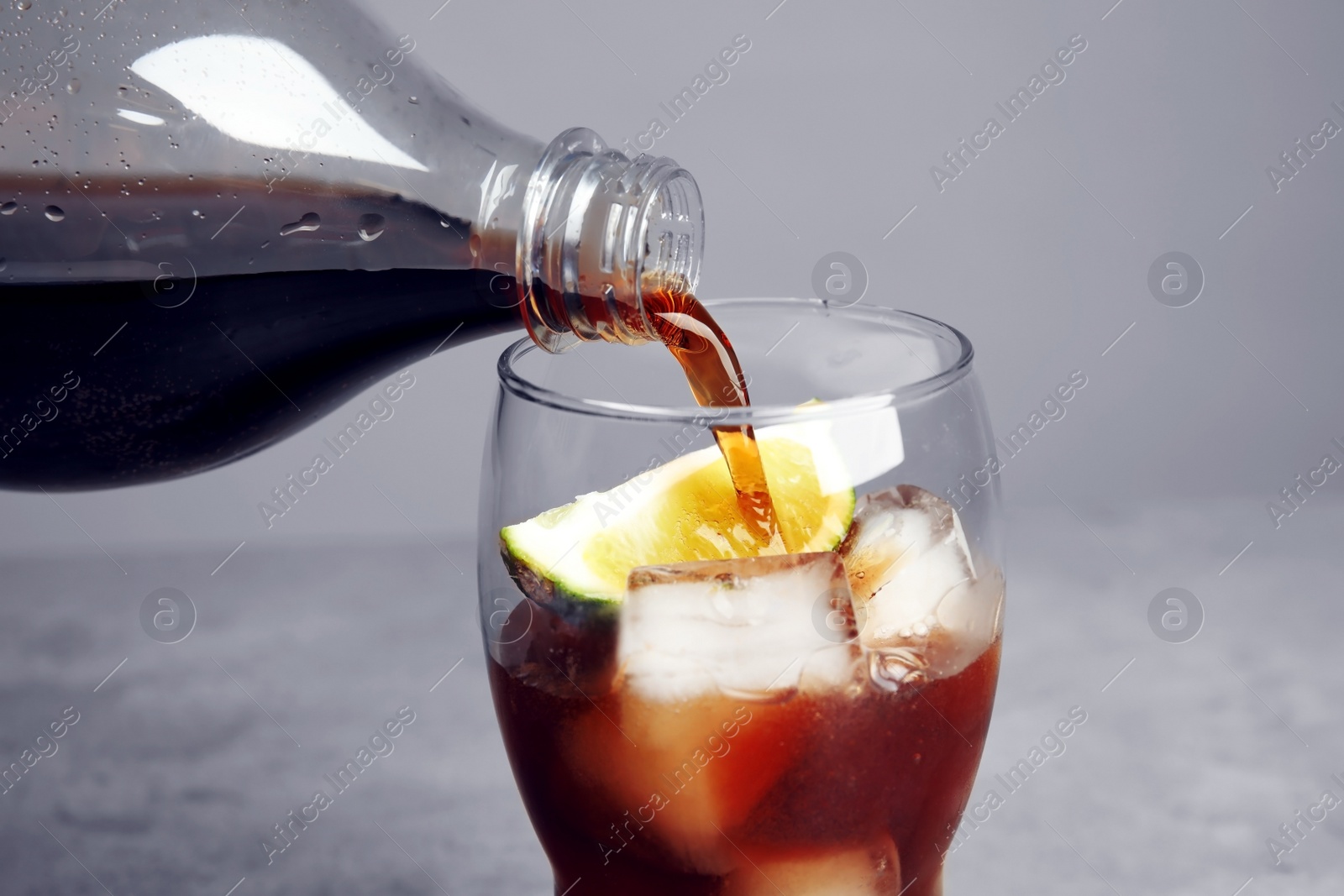 Photo of Pouring refreshing soda drink into glass on table, closeup