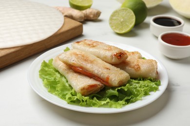 Photo of Delicious fried spring rolls served on white marble table