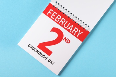 Photo of Top view of calendar with date February 2nd on light blue background. Groundhog day