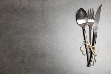 Photo of Silver cutlery on gray background, top view. Table setting
