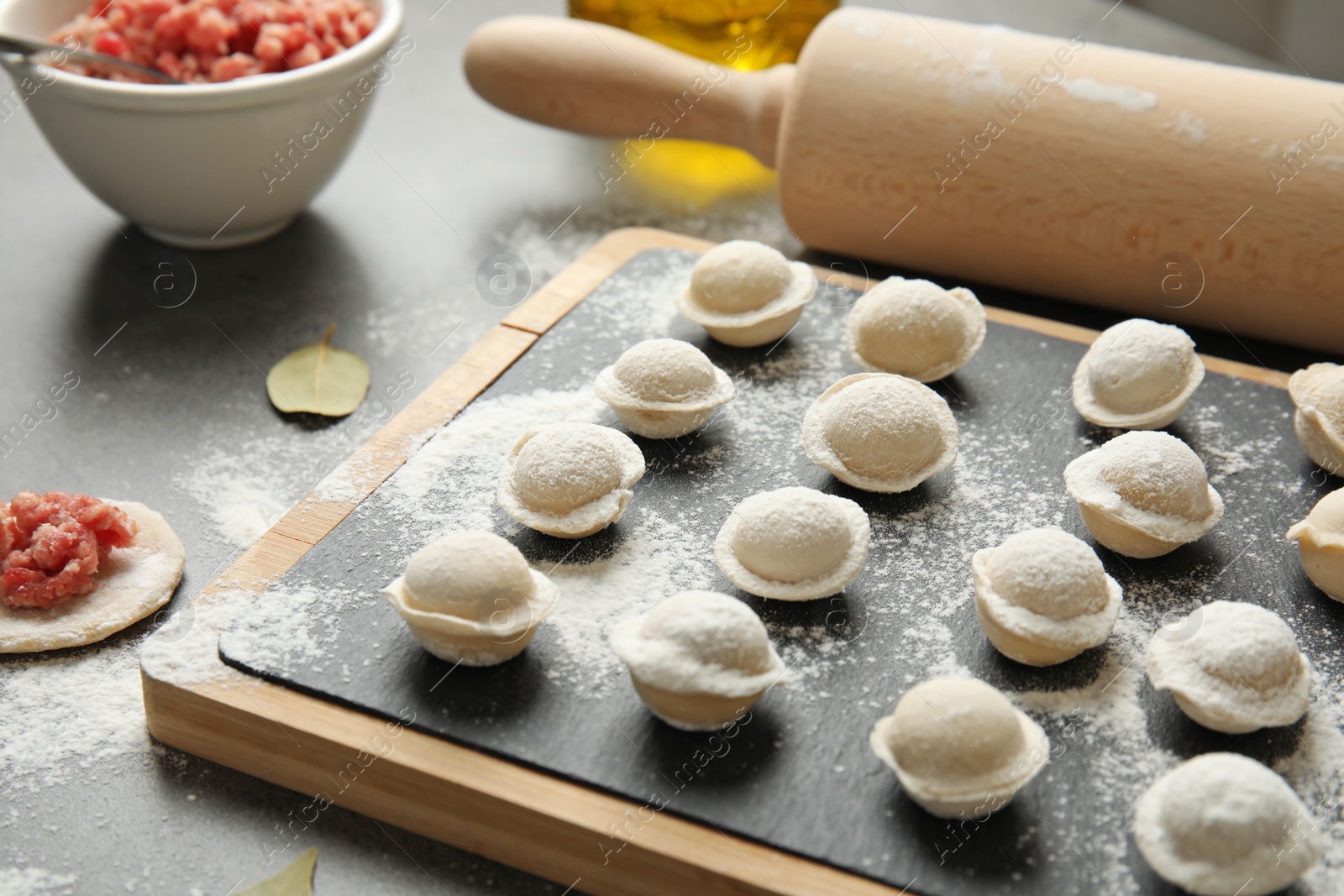 Photo of Board with raw dumplings on table, closeup. Process of cooking