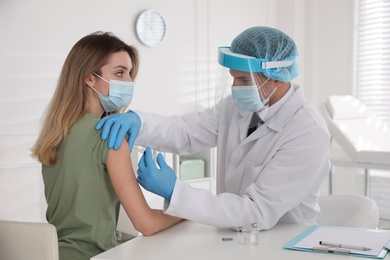 Doctor vaccinating young woman against Covid-19 in clinic