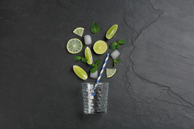 Photo of Creative lemonade layout with lemon slices, ice and mint on black table, top view