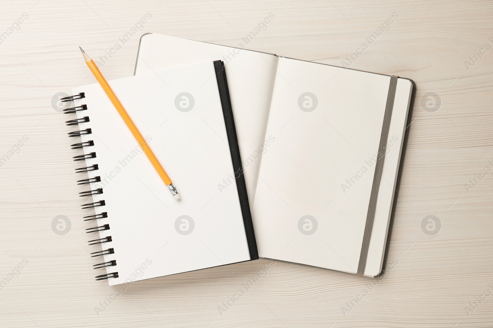 Photo of Notebooks and pencil on white wooden table, top view