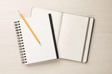 Photo of Notebooks and pencil on white wooden table, top view