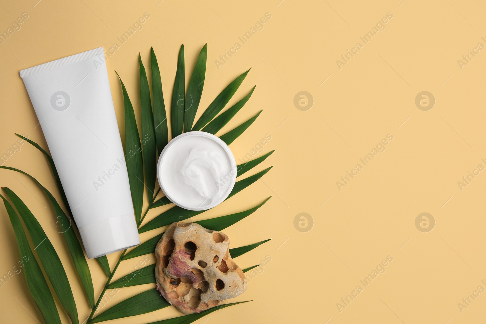 Photo of Cosmetic products, palm leaf and beautiful stone on beige background, flat lay. Space for text