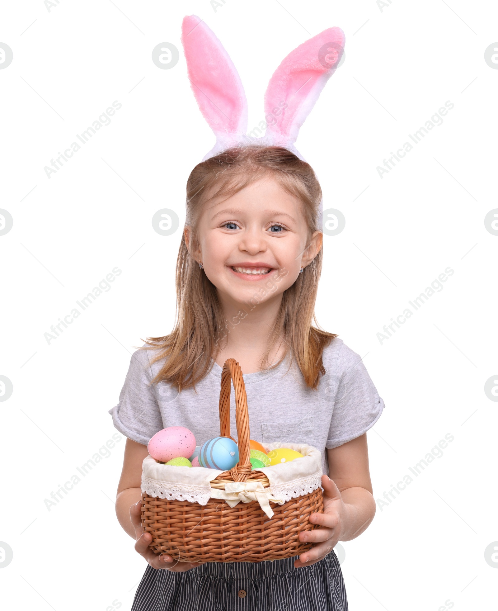 Photo of Easter celebration. Cute girl with bunny ears and wicker basket full of painted eggs isolated on white