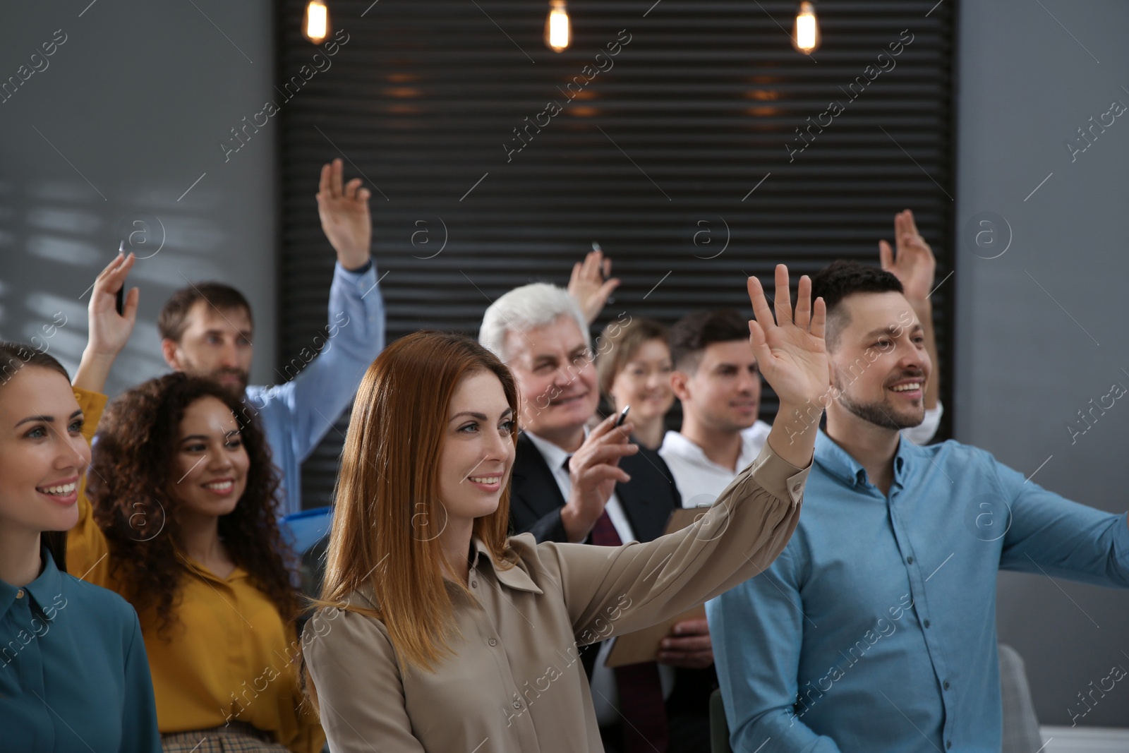 Photo of People raising hands to ask questions at seminar in office