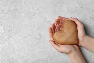 Photo of Woman holding heart on grey stone background, top view with space for text. Donation concept