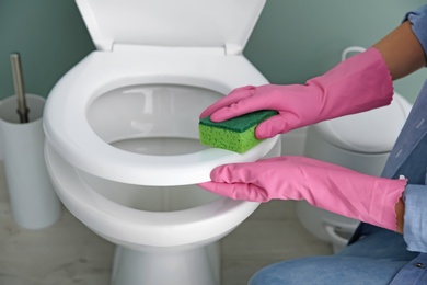 Photo of Woman cleaning toilet bowl in bathroom