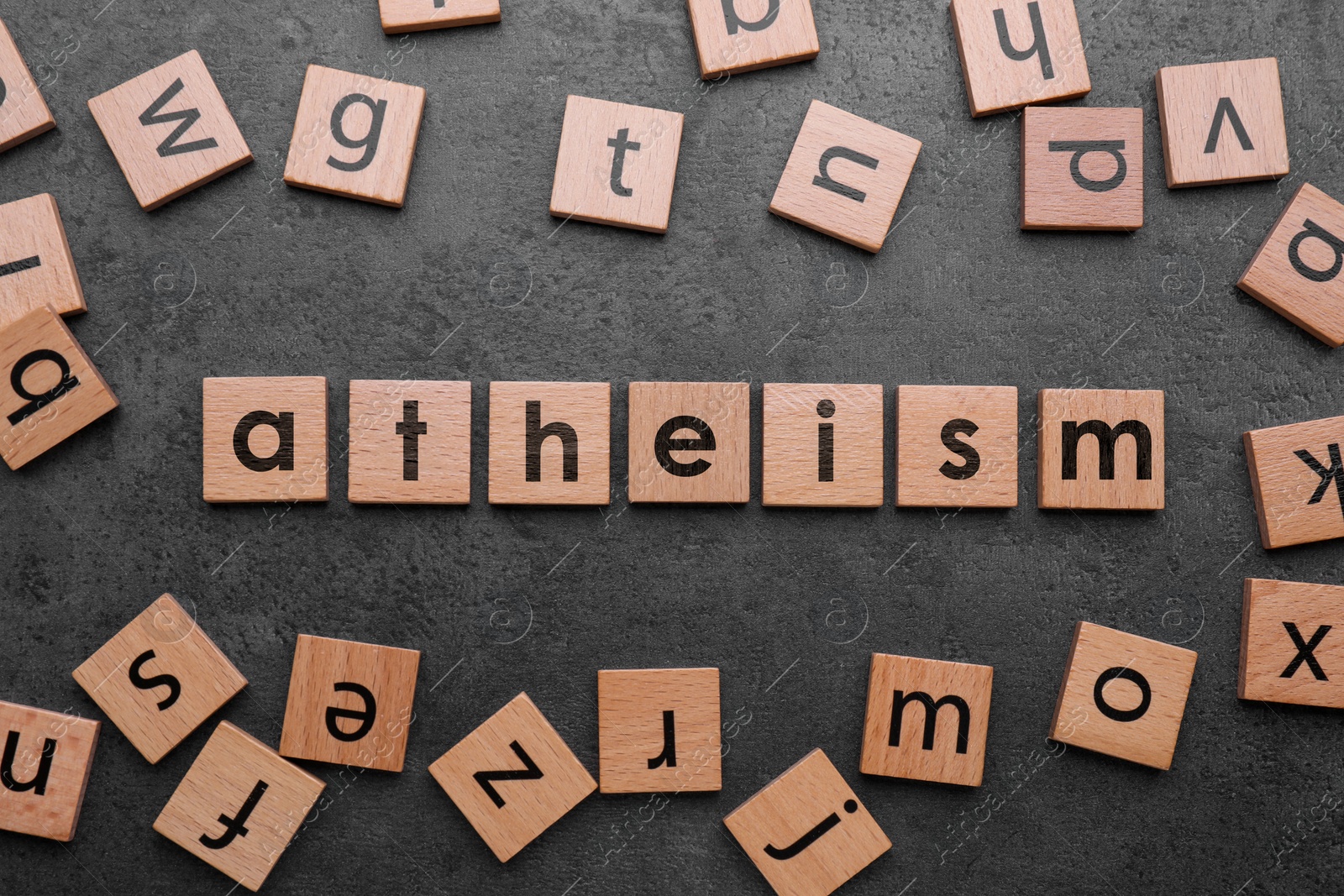 Image of Word Atheism made of wooden squares with letters on grey textured table, flat lay