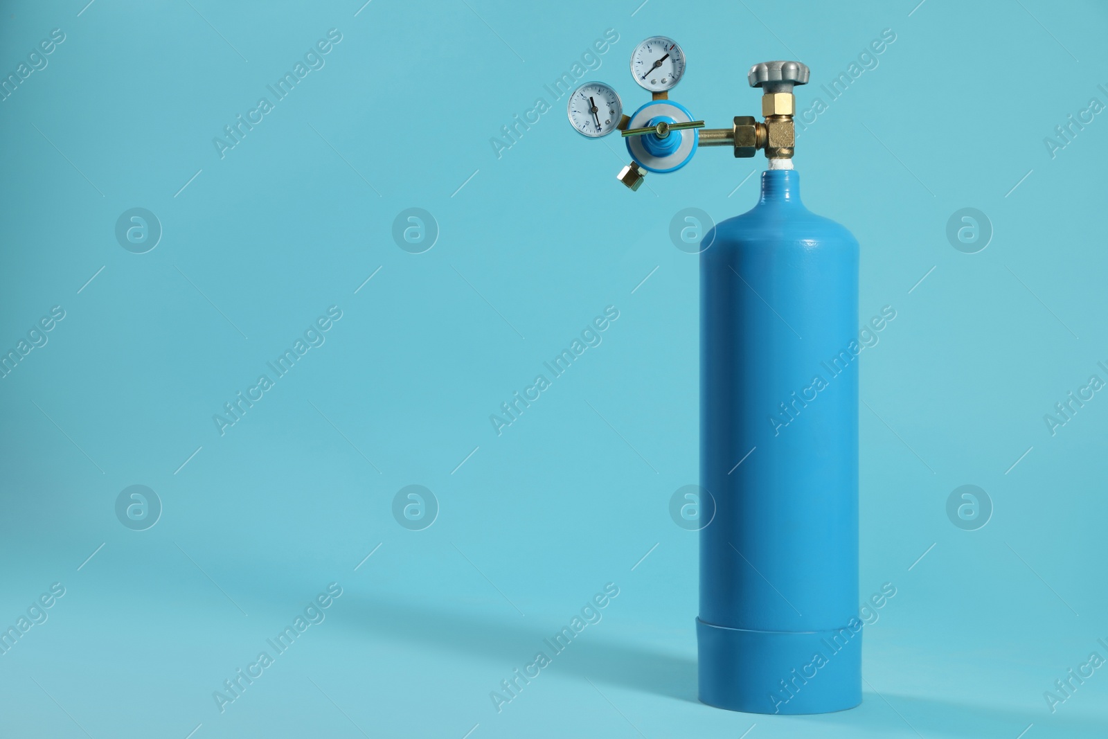 Photo of Medical oxygen tank on light blue background. Space for text