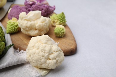 Photo of Various cauliflower cabbages on light grey table, space for text