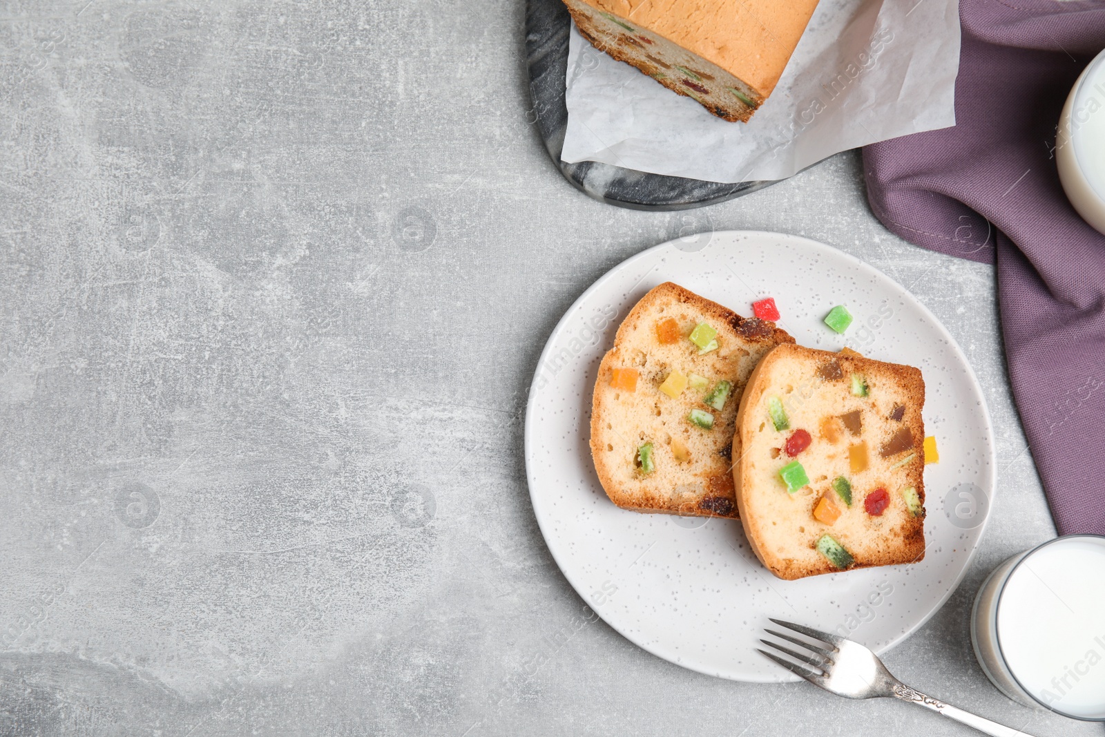 Photo of Delicious cake with candied fruits and milk on light grey table, flat lay. Space for text