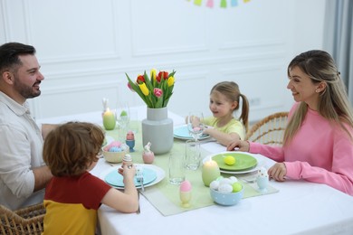 Photo of Cute family celebrating Easter at served table in room
