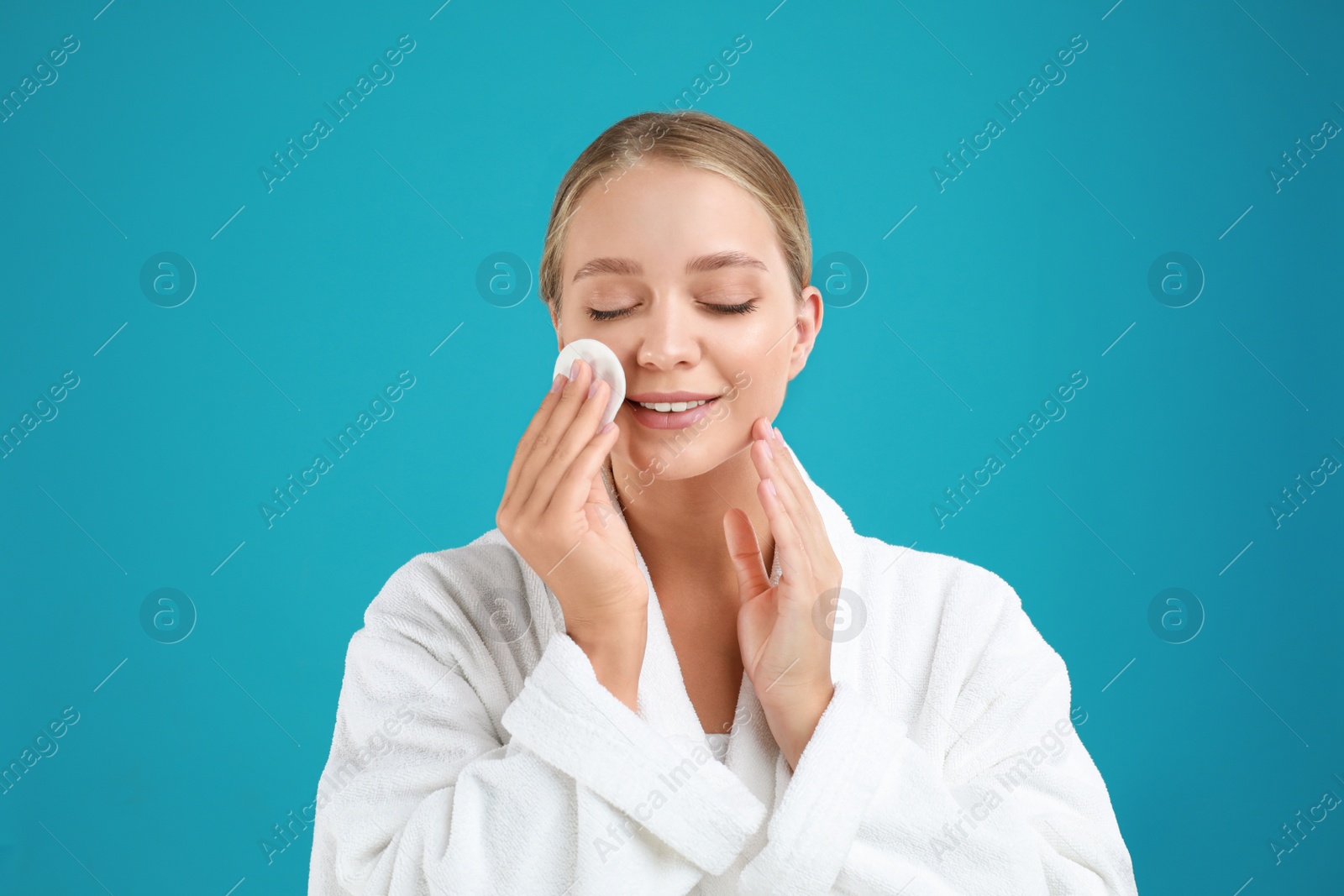 Photo of Beautiful young woman with cotton pad on turquoise background