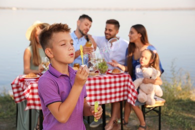 Little boy blowing bubbles outdoors. Picnic time