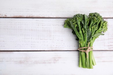 Fresh raw broccolini on white wooden table, top view and space for text. Healthy food