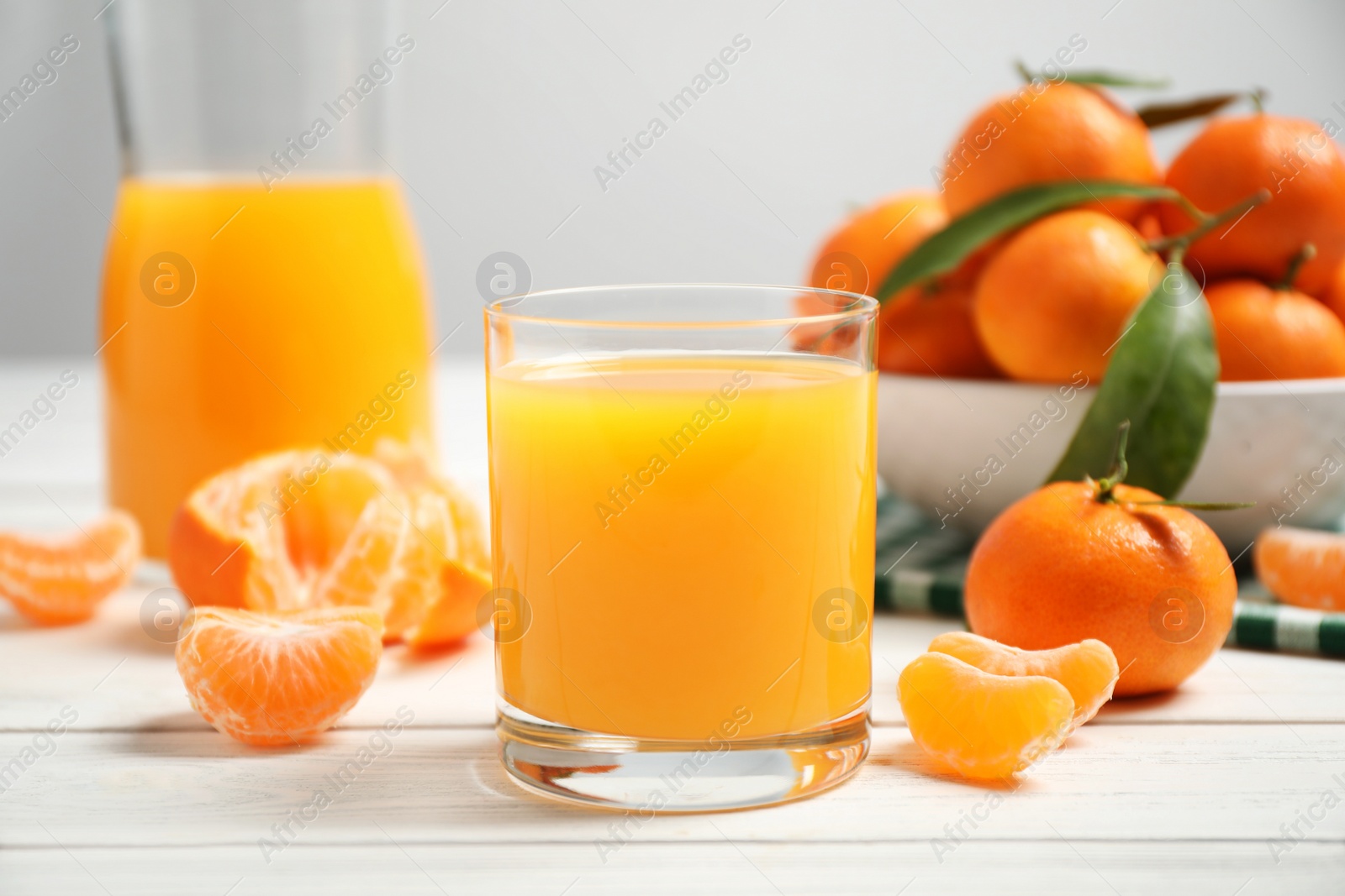 Photo of Glass of fresh tangerine juice and fruits on white wooden table