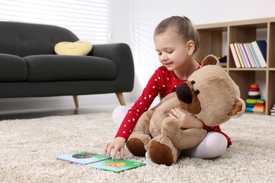 Photo of Cute little girl playing with teddy bear at home. Space for text