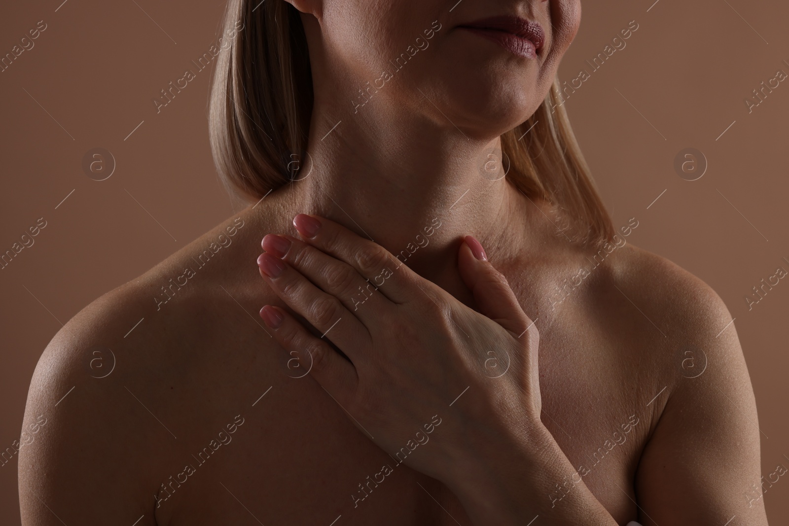 Photo of Beautiful woman touching her neck on beige background, closeup