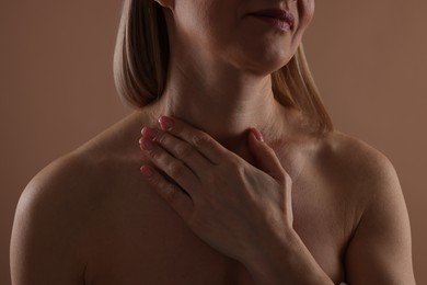 Beautiful woman touching her neck on beige background, closeup