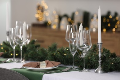 Christmas table setting with burning candles and festive decor in room