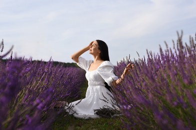 Photo of Beautiful young woman sitting in lavender field