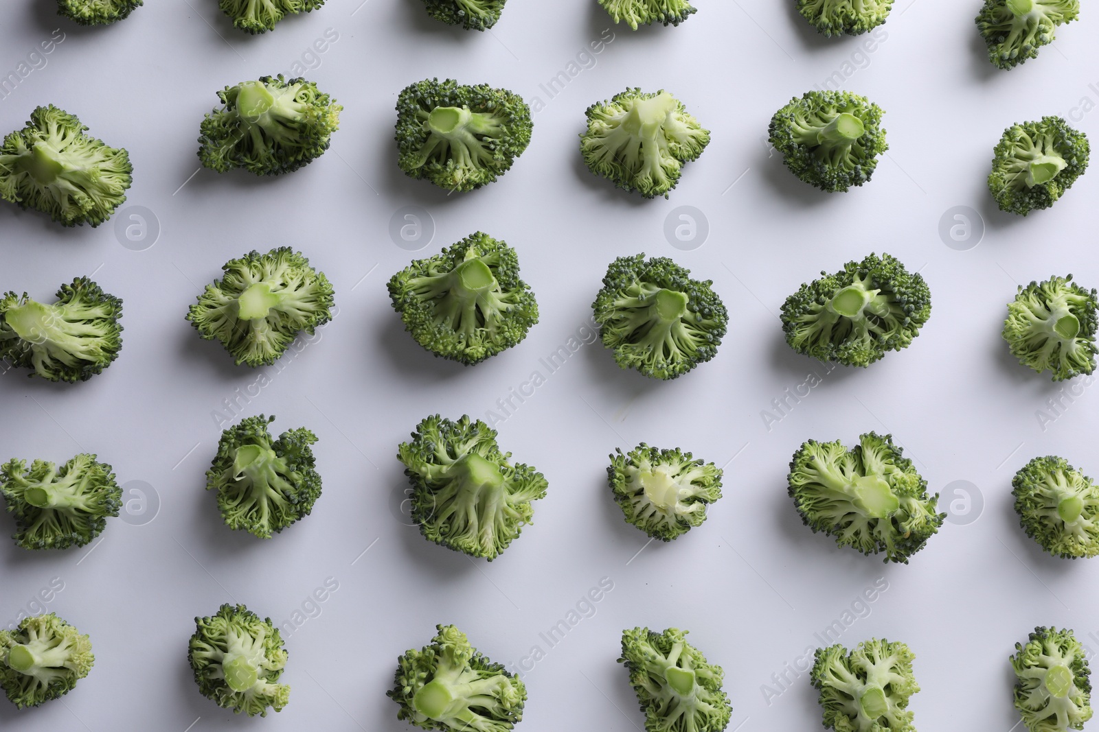 Photo of Many fresh green broccoli pieces on white background, flat lay