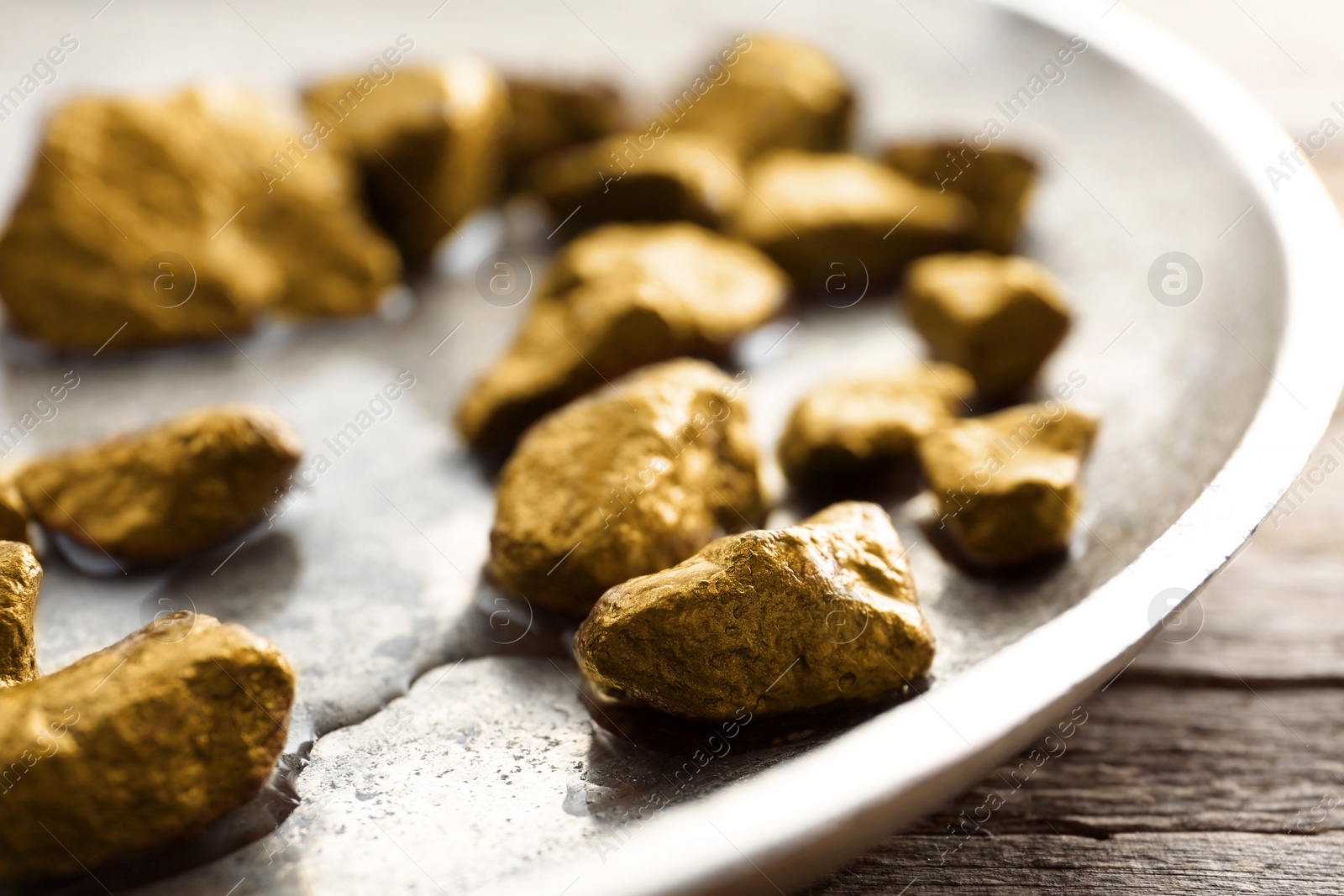 Photo of Plate with gold nuggets and water on table, closeup