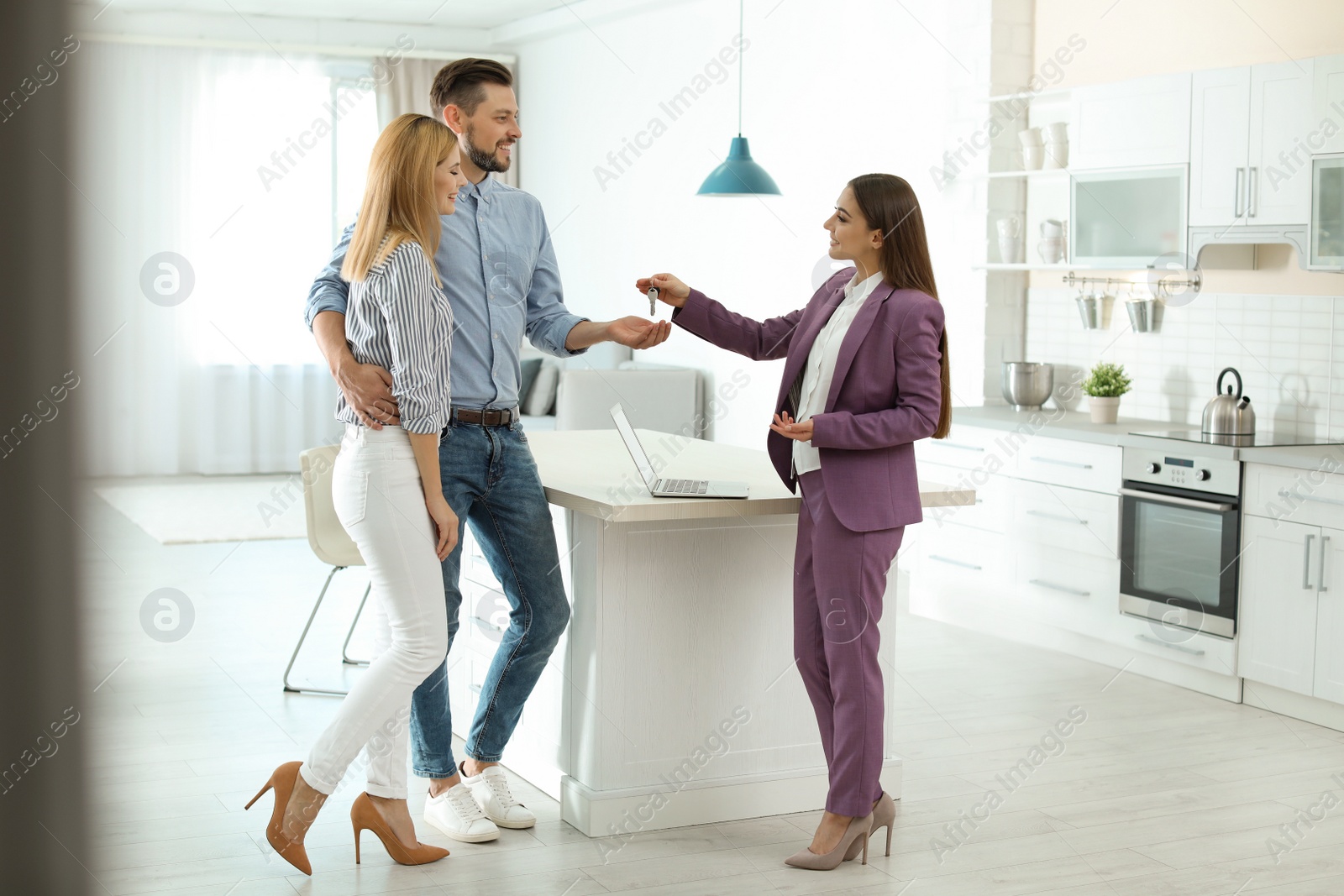 Photo of Female real estate agent giving house key to couple indoors