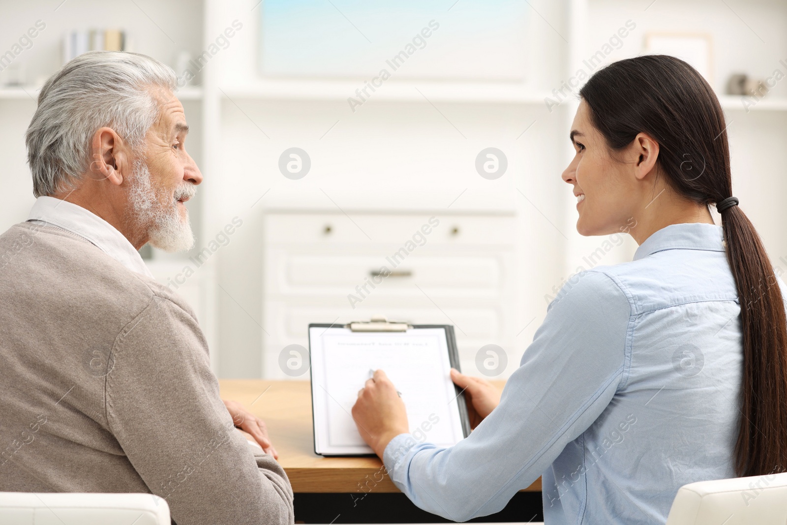 Photo of Smiling notary consulting senior man about Last Will and Testament in office, back view