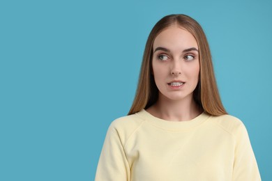 Photo of Portrait of embarrassed young woman on light blue background, space for text