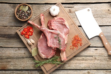 Photo of Fresh tomahawk beef cuts, butcher knife and spices on wooden table, top view