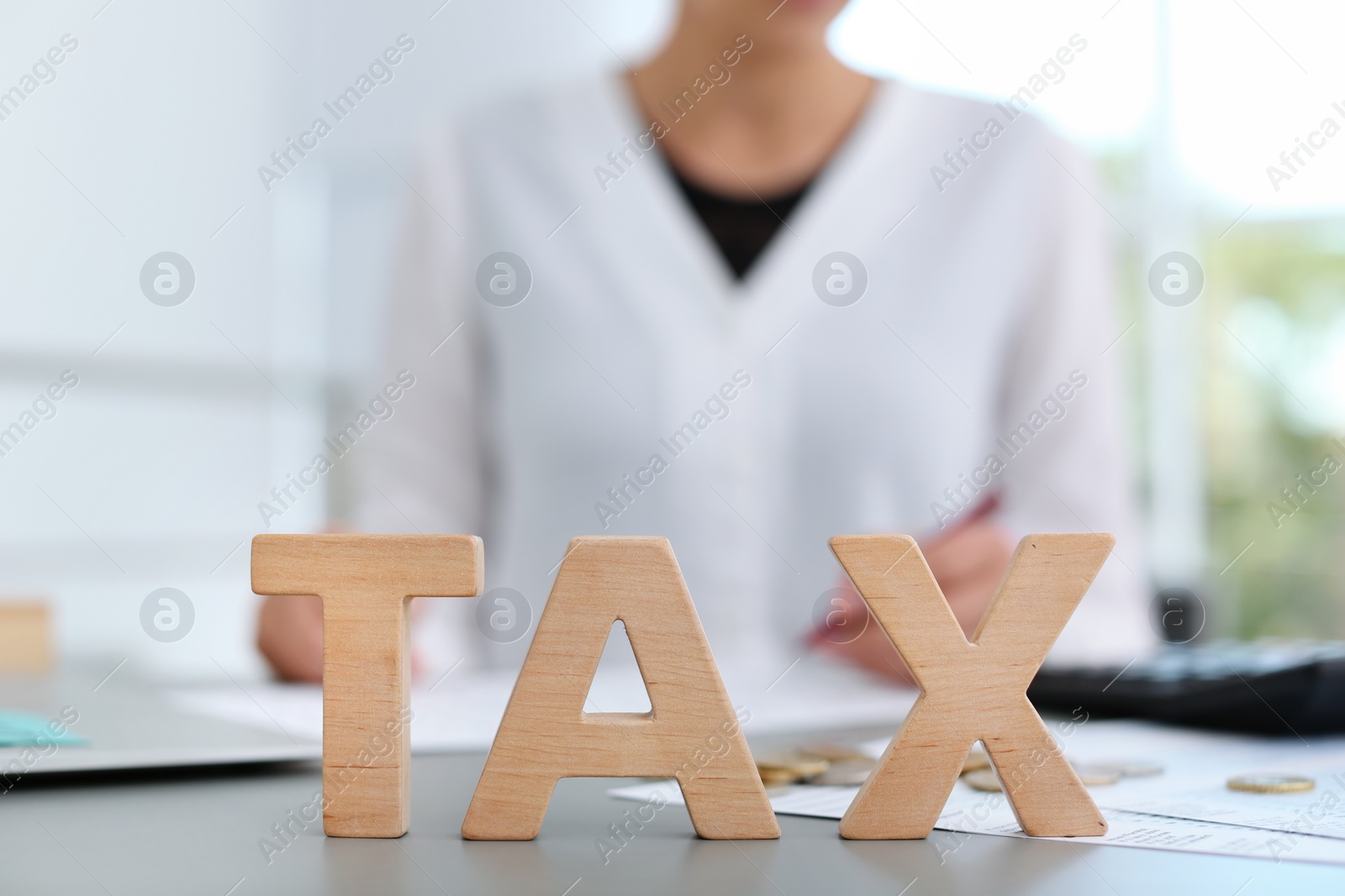 Photo of Word TAX an blurred woman on background