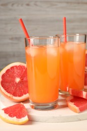 Photo of Tasty freshly made grapefruit juice and fruits on white table