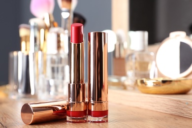 Photo of Lipsticks in gold tubes on dressing table, space for text