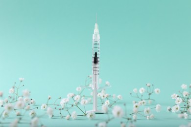 Cosmetology. Medical syringe and gypsophila flowers on turquoise background